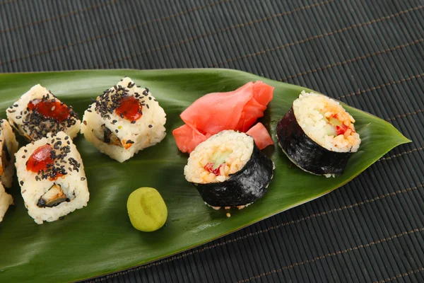 Sabroso sushi Maki - Roll on green leaf on wooden table close-up —  Fotos de Stock