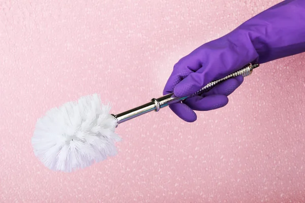 Toilet brush in hand on pink background — Stock Photo, Image