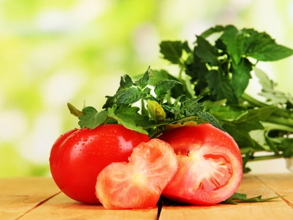 Frische Tomaten und junge Pflanze auf Holztisch vor natürlichem Hintergrund — Stockfoto