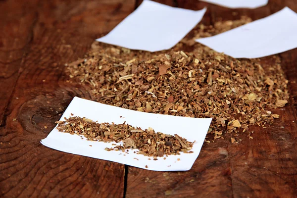 Tabaco e papel para enrolar, sobre fundo de madeira — Fotografia de Stock