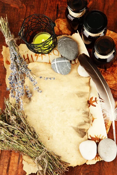 Composition with old papers, herbs, stones and bottles with symbols on wooden background — Stock Photo, Image