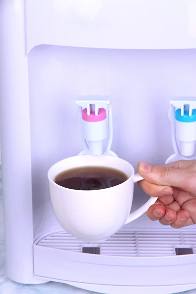 Copo de enchimento da mulher no refrigerador de água — Fotografia de Stock