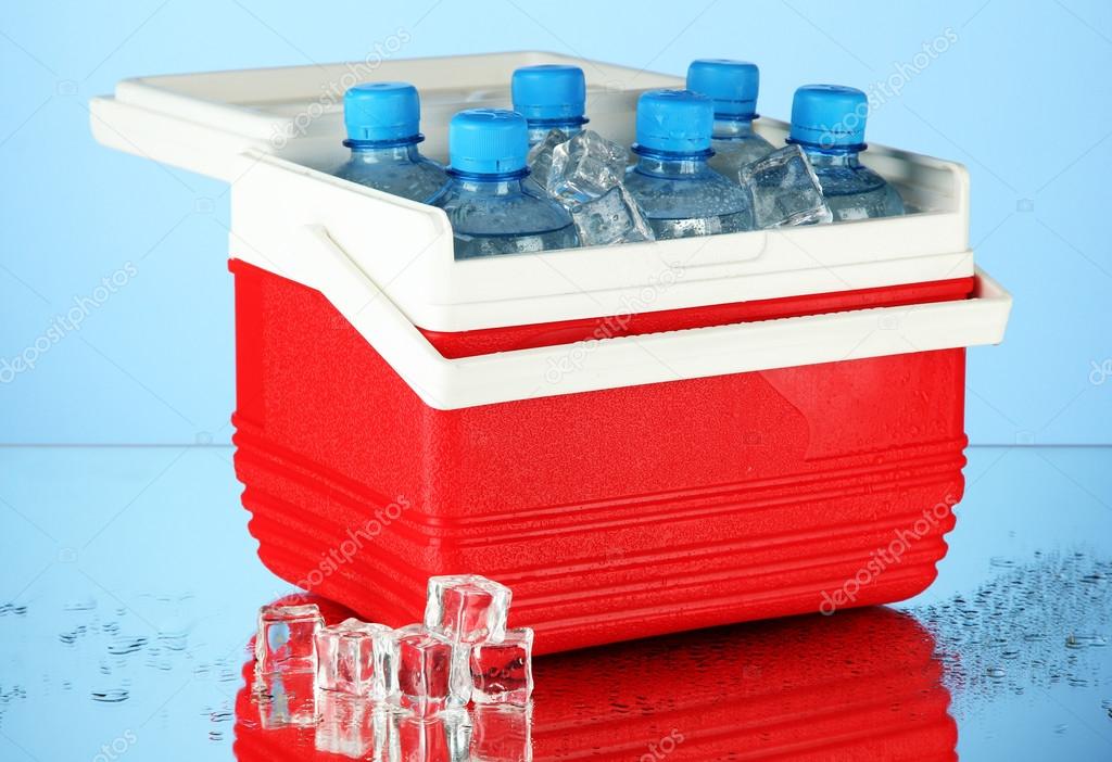 Traveling refrigerator with bottles of water and ice cubes, on blue