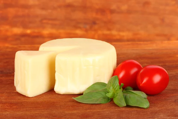 Cheese mozzarella,basil and tomato on wooden background — Stock Photo, Image