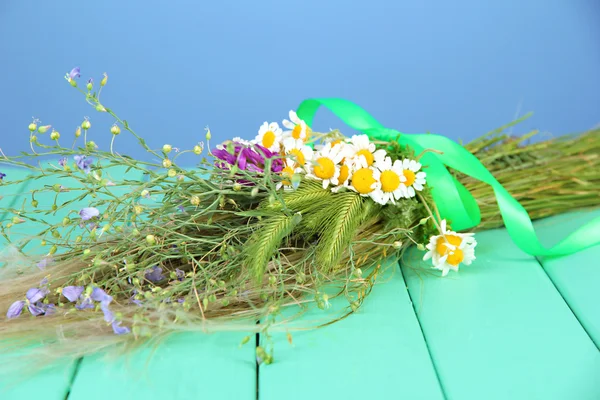 Buket bunga liar dan tanaman herbal, di atas meja kayu dengan latar belakang warna — Stok Foto