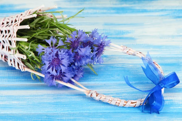 Mooi boeket van korenbloemen in mand op blauwe achtergrond — Stockfoto