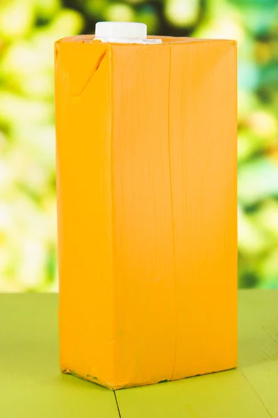 Pacote de suco na mesa no fundo brilhante — Fotografia de Stock