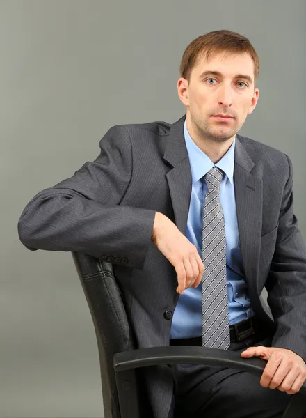 Young businessman on grey background — Stock Photo, Image