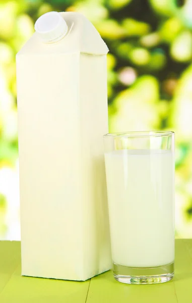 Pacote de leite na mesa no fundo brilhante — Fotografia de Stock