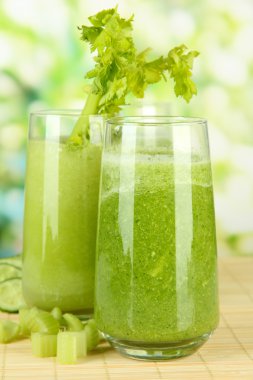 Bambu mat yeşil zemin üzerine yeşil kereviz suyu bir bardak