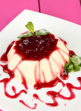 Panna cotta renk ahşap zemin üzerinde frambuaz sos ile