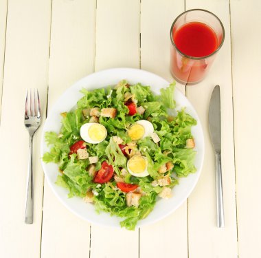 renkli ahşap zemin üzerinde beyaz tabakta Sezar salatası