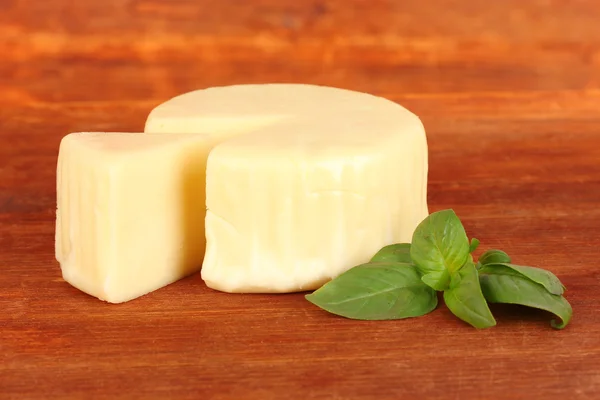 Sýr mozzarella a bazalkou na dřevěné pozadí — Stock fotografie