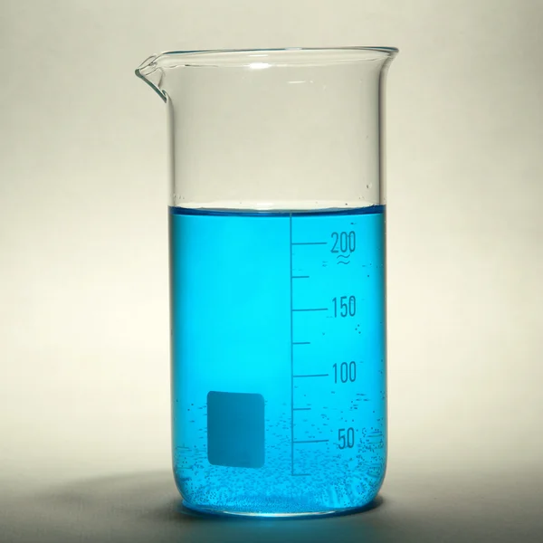 Tubo de ensayo con líquido azul sobre fondo gris — Foto de Stock