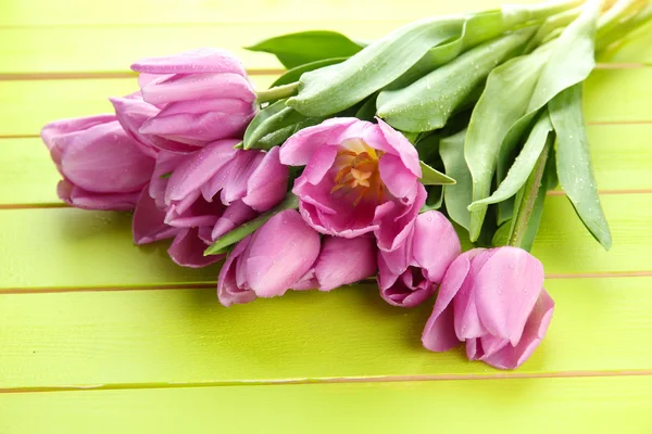 Belo buquê de tulipas roxas no fundo de madeira verde — Fotografia de Stock