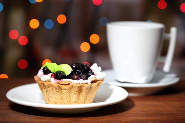 Tasty blackberry cake and cup of beverage, on dark background with bokeh defocused lights