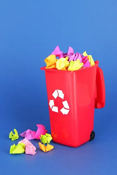 Corbeille de recyclage avec papiers sur fond bleu — Photo