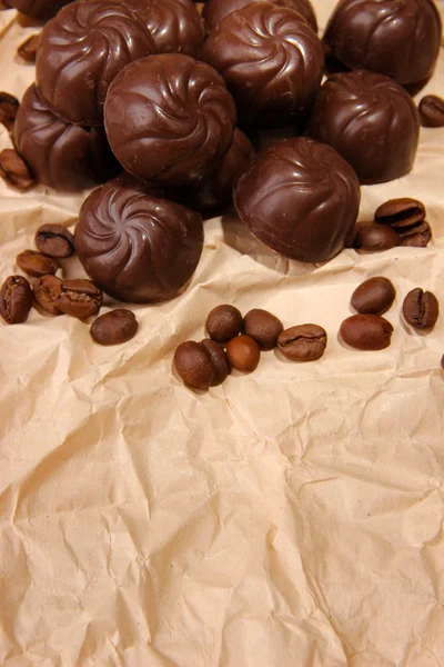 Caramelle al cioccolato e chicchi di caffè, su sfondo di carta beige — Foto Stock