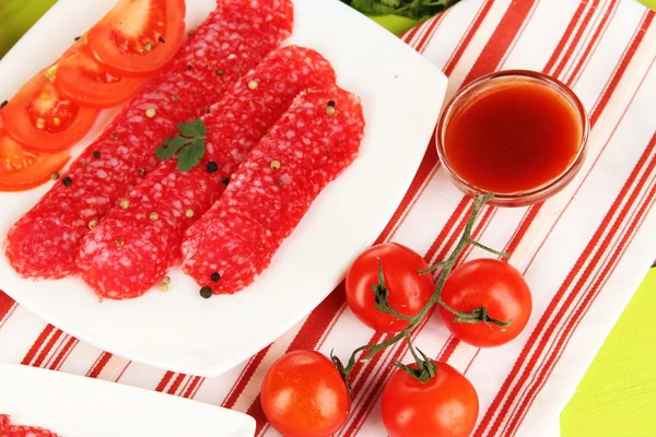 Tasty salami on plate on wooden table close-up — Stock Photo, Image