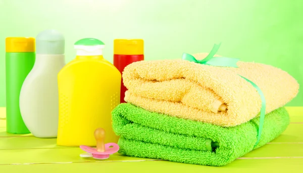 Cosméticos para bebés y toallas sobre mesa de madera, sobre fondo verde —  Fotos de Stock