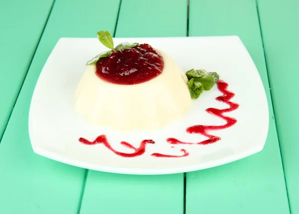 Panna Cotta с малиновым соусом, на цветном деревянном фоне — стоковое фото