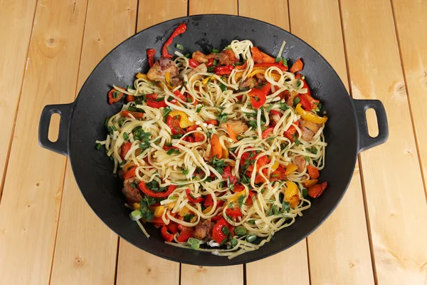 Macarrão com legumes em wok no fundo de madeira — Fotografia de Stock