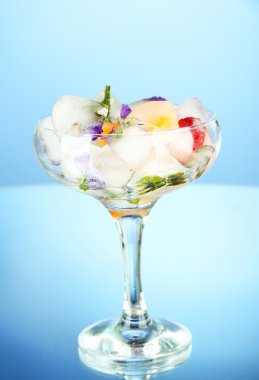 çiçekler, otlar ve mavi zemin üzerine kokteyl bardak içine meyve buz