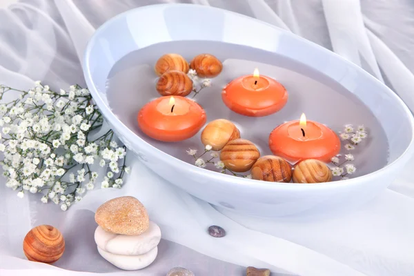 Mooie kaarsen zwemmen in de mooie plaat op houten tafel close-up — Stockfoto