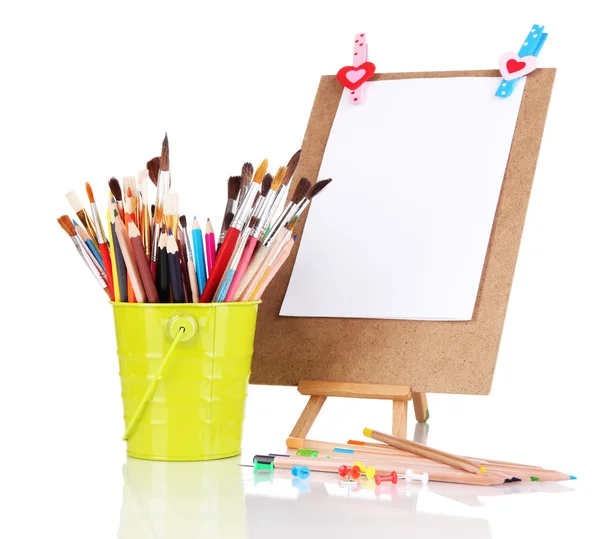 Pequeño caballete con hoja de papel con materiales de arte aislados en blanco —  Fotos de Stock