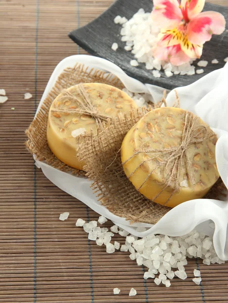 Hand-made soap and sea salt on grey bamboo mat — Stock Photo, Image