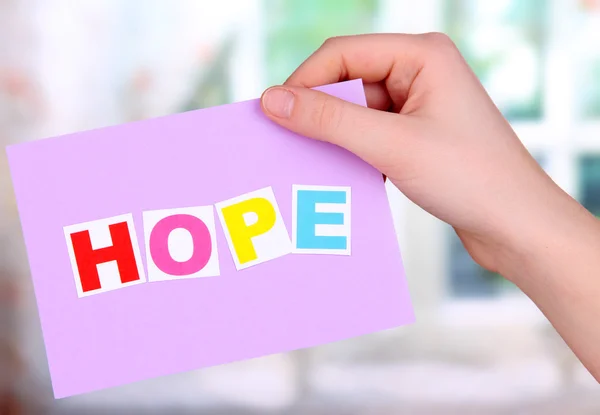 Hope word on piece paper in hand on window background — Stock Photo, Image