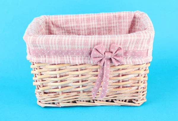 Wicket basket with pink fabric and bow, on color background — Stock Photo, Image