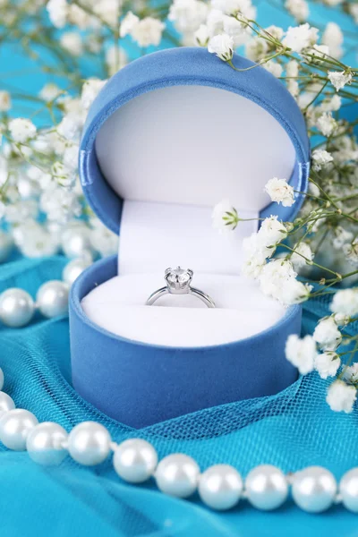 Flores e anel de noivado em pano azul — Fotografia de Stock
