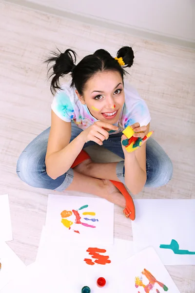 Young pretty painter with hands in paint, on gray background — Stock Photo, Image