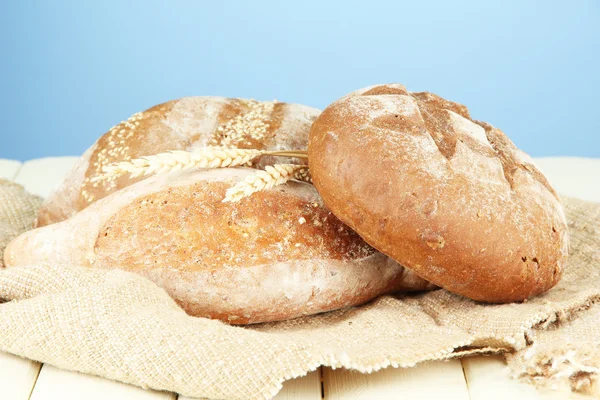 Sammansättning med bröd och säckväv på träbord, på färgbakgrund — Stockfoto