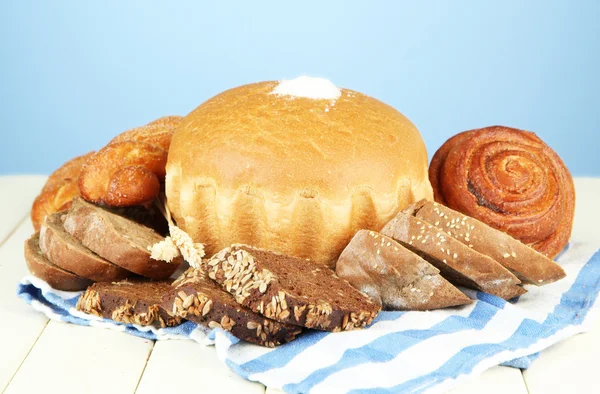 Samenstelling met brood, broodjes en servet op houten tafel, op een achtergrond met kleur — Stockfoto