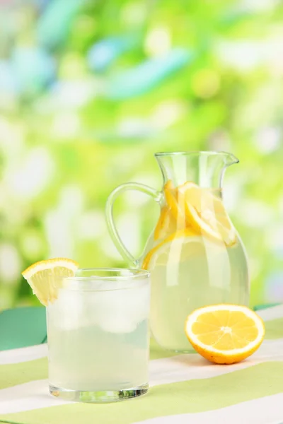 柑橘柠檬汁在投手和自然背景上的木桌上的眼镜 — 图库照片