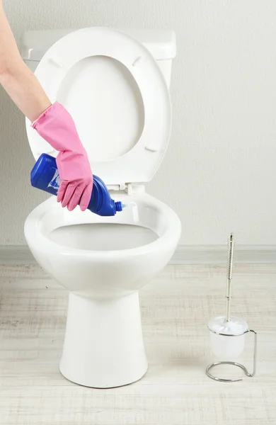 Mulher mão com spray garrafa de limpeza de um vaso sanitário em um banheiro — Fotografia de Stock