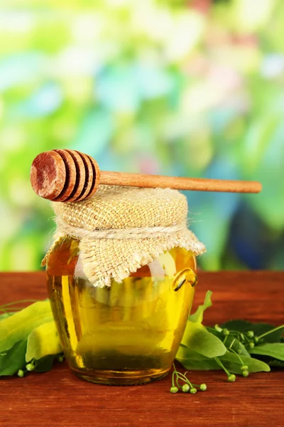 Pot met honing met bloemen van kalk, op houten tafel op lichte achtergrond — Stockfoto