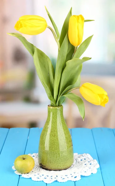 Yellow tulips in vase on wooden table on room background — Stock Photo, Image