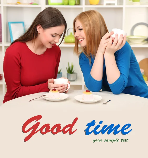 Two girl friends talk and drink tea in kitchen — Stock Photo, Image