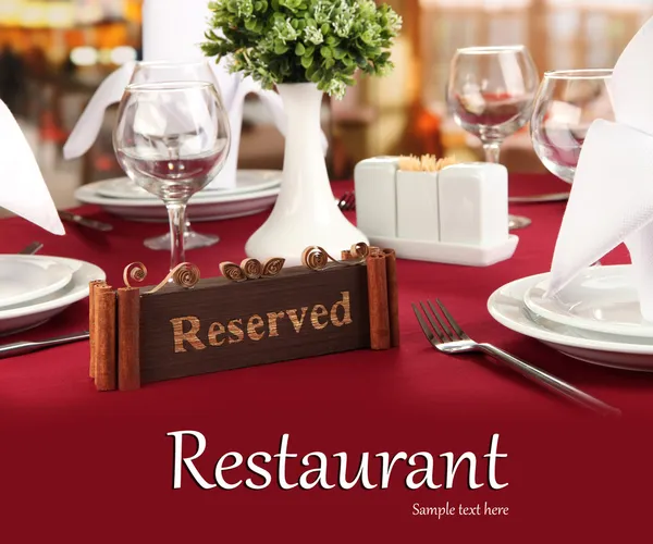 Reserved sign on restaurant table with empty dishes and glasses — Stock Photo, Image