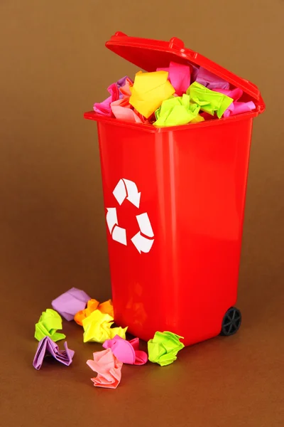 Recycling bin with papers on brown background — Stock Photo, Image