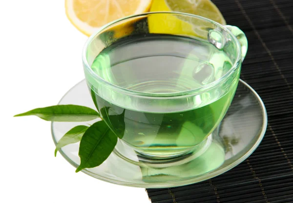 Xícara transparente de chá verde com limão no tapete de bambu, isolado em branco — Fotografia de Stock