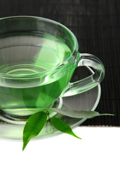 Taza transparente de té verde en estera de bambú, aislada en blanco —  Fotos de Stock