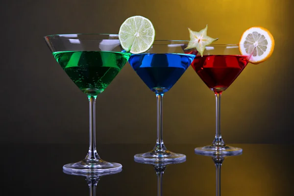 Alkoholische Cocktails in Martinigläsern auf dunkelgelbem Hintergrund — Stockfoto