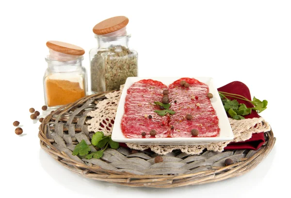 Tasty salami on plate on wicker cradle isolated on white — Stock Photo, Image