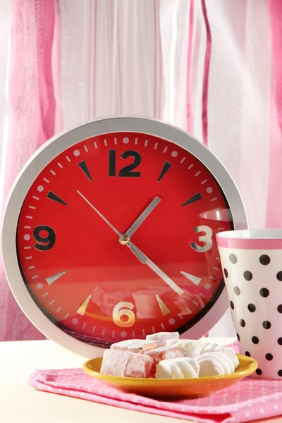 Cup tea and clock on bright background — Stock Photo, Image