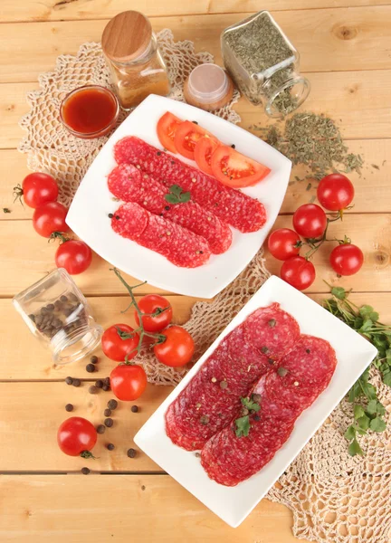 Leckere Salami auf Tellern auf Holztisch in Großaufnahme — Stockfoto