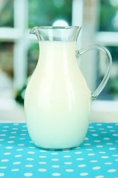 Pitcher of milk on table in room — Stock Photo, Image